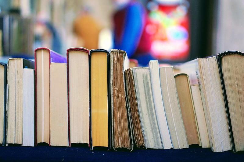 A row of used books lying spines up on a table